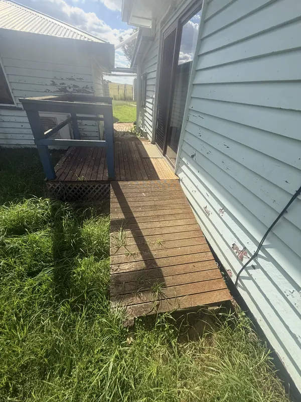 Old weathered timber walkway beside a house, before
